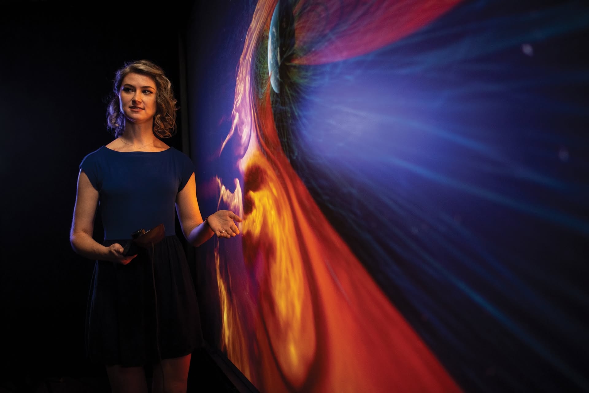 Kalina Borkiewicz presenting beside a large scientific visualization